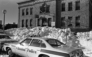 Boston Police vehicle and snowdrifts in front of District 14 Boston Police Headquarters on Washington Street