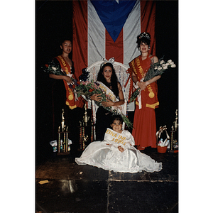 Four women who were awarded titles pose with crowns and flowers at the Festival Puertorriqueño