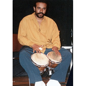 Portrait of an unidentified man playing bongo drums.