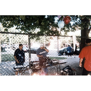 Two men setting up a sound system outside in the Villa Victoria neighborhood playground.
