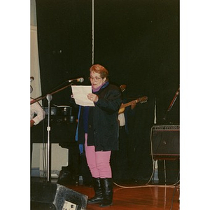 Woman reads from a piece of paper on stage at the Jorge Hernandez Cultural Center.