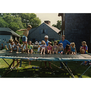 A boy jumping on a trampoline while others watch during a Boys and Girls Club Board outing
