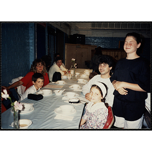 Several adults and children seated at a table look at the camera while a girl stands beside them during a Boys & Girls Club Awards Night