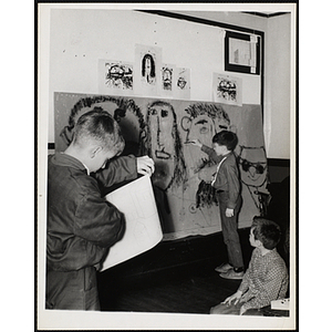 A boy in the foreground holds a sketch of a house while another works on a large drawing for his art class at the Charlestown Boys' Club