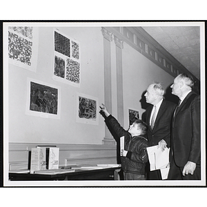 Richard Nee points to his entry in the Boys' Clubs of Boston Fine Arts Exhibit to two Selection Committee members Richard H. Bassett, center, and John G. Clinch at the South Boston Branch of the National Shawmut Bank