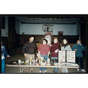 A boy and adults stand behind a display table during an alcohol awareness event