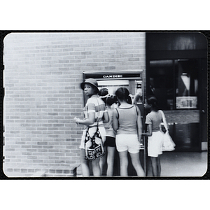 A group of girls stand at a candy vending machine