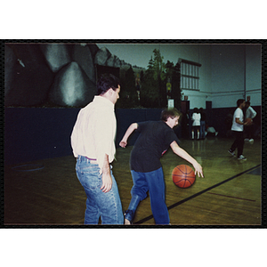 A boy plays basketball with a man