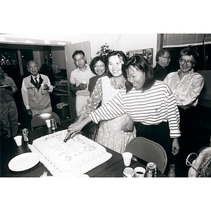 Two women cutting a cake at the victory party celebrating Dynasty Restaurant workers receiving their back wages