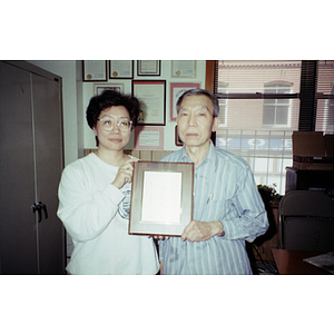 Association members hold a plaque while standing in their office