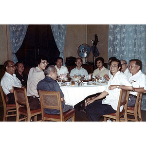 Men and women sit around a dinner table and smile during a dinner party in Guangzhou, China