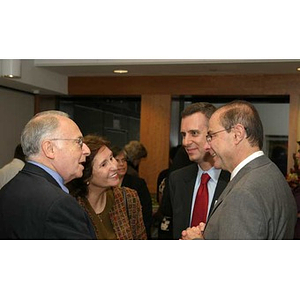 Three people converse with President Aoun at the Torch Scholars dinner