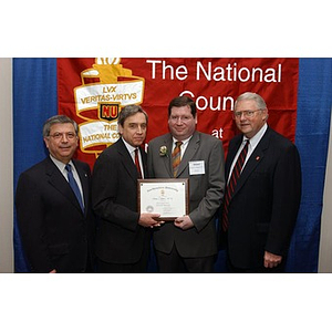 An inductee poses with his certificate and others at The National Council Dinner