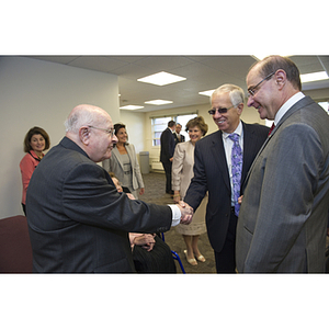 Dr. George J. Kostas shakes hands with a man at the groundbreaking for the George J. Kostas Research Institute for Homeland Security