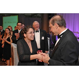 A young woman presenting President Aoun with a small gift at a dinner honoring members of the Huntington Society