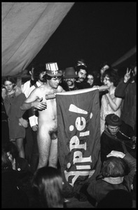 Yippies on stage at the Counter-inaugural Ball, 1969: naked man in an Uncle Sam hat and comrades unfurl a Yippie! flag