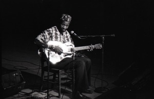 Taj Mahal in concert at Northfield, Mass.: Taj Mahal seated, playing steel guitar