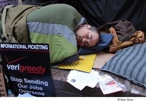 Occupy Wall Street: man sleeping by sign reading, 'verigreedy, stop sending our jobs oversees'