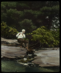 Orient Brook: Waugh playing the flute on a rock by a stream