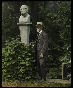 Geo. W. Cable (elderly man standing in front of stone bust in garden)