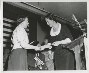 Unidentified staff member handing gift to client on stage at Institute Day