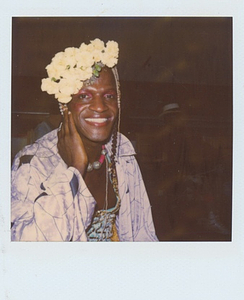 A Photograph of Marsha P. Johnson Smiling and Wearing a Patterned Purple Jacket