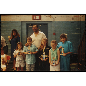 A boy and four girls stand with a man, displaying their trophies at a Boys and Girls Club awards event