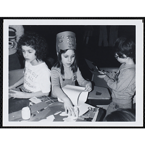 Ten boys sit and stand around a table, working on projects for their arts and crafts class at the Boys and Girls Clubs of Boston