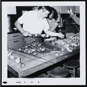 A man and boy skewer kabobs in a kitchen