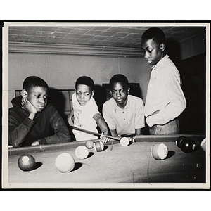 Group of four boys playing a game of pool