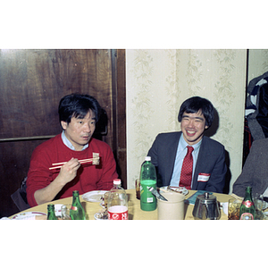 Two men eat at a restaurant table during a Chinese Progressive Association celebration of the Chinese New Year