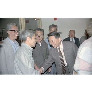 Member of the Consulate General of the People's Republic of China shakes hands with several attendees at a welcome party held for the Consulate General's visit to Boston