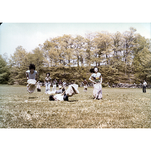 Two girls jump across a rope during a sack race, while another girl falls to the ground between them