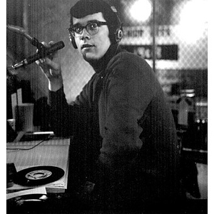 Young man at microphone wearing headphones in the broadcast booth at the WNEU studio