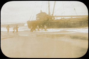 Men in the surf with a beached vessel