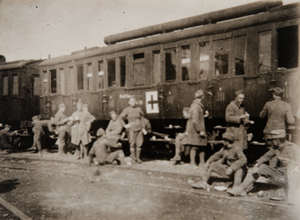 Soldiers gathered alongside a stationary train [marked with a Red Cross?]