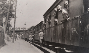 German, Turkish and Bulgarian prisoners leaning out the windows of a train pulled into a station