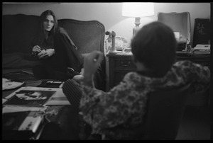 Judy Collins, seated on a bed at the Beverley Hills Hotel, talking with an unidentified man