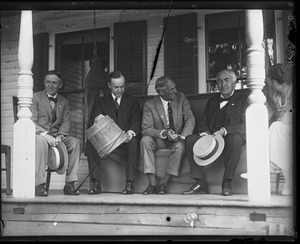 Harvey Firestone, Calvin Coolidge (with sap bucket), Henry Ford, and Thomas Edison (l. to r.) seated on a porch, Grace Coolidge looking on