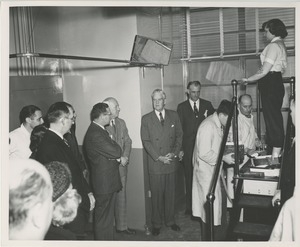 A technician makes a mold of a woman's foot for a prosthetic device as a large group of people, including Bruce Barton, look on