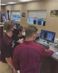 Springfield College Athletic Training Students looking at scan of hand (ca. 2023)