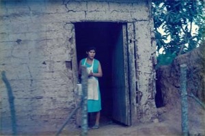 A woman stands in a doorway in a rural village in El Salvador