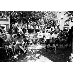 Villa Victoria residents sitting in chairs outside in the shade.