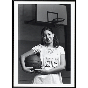 A teenage girl from the Boys and Girls Clubs of Boston posing in a "Junior Celtics" jersey with a basketball under her arm