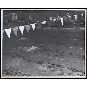 A teenage boy participates in a race in a natatorium pool