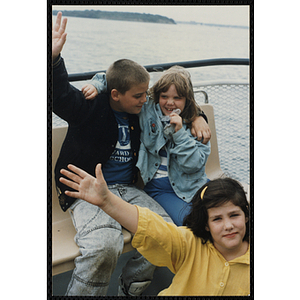 A boy and two girls pose on the deck of a boat