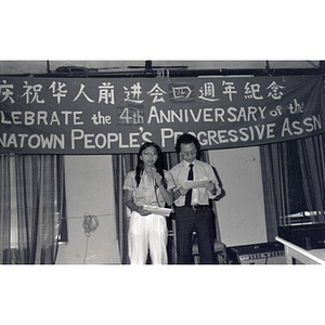 Man and woman address an audience at the Chinese Progressive Association's Fourth Anniversary Celebration