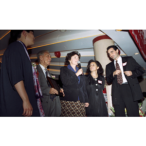 Man holds an award plaque next to a woman speaking from microphone at Chinese Progressive Association's 20th Anniversary Celebration