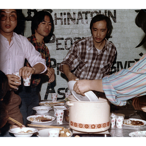 Men serve food from a hotpot at the Chinese Progressive Association's office