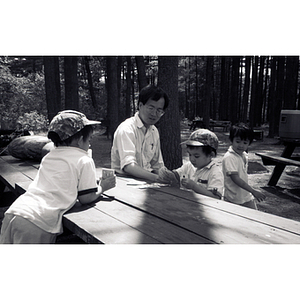 Man and children sit together at a picnic table